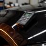 Gloss meter resting on a polished dark fender