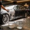 Foam wash stage on a black car under studio lighting