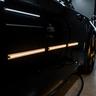 Finished car panel reflecting strip lights in the studio bay
